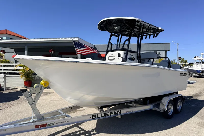 The Image of 2025 Sea Pro 225FLX Sandbar boat on trailer, displayed outdoors with American flag. - 1