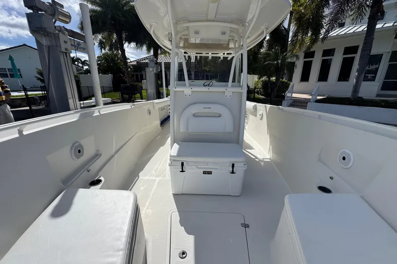 Slide: The Image of 2016 Sailfish 320 CC boat interior with seating and storage, docked near palm trees. - 12
