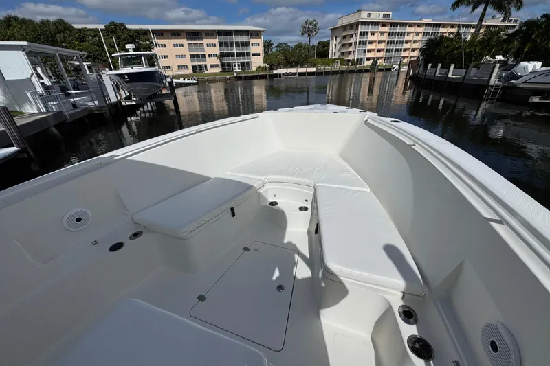 Slide: The Image of 2016 Sailfish 320 CC boat interior with white seating, docked near waterfront buildings. - 13