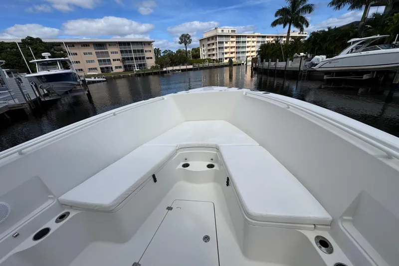 Slide: The Image of 2016 Sailfish 320 CC boat interior with white seating, docked near waterfront buildings. - 15