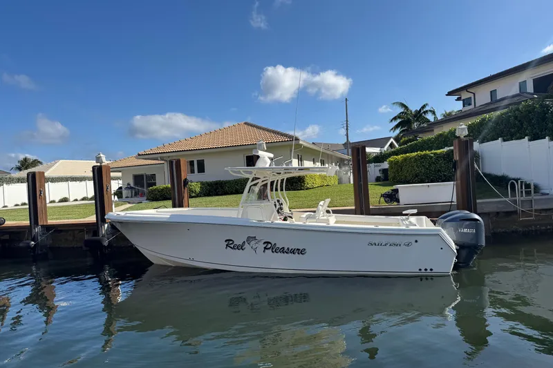 Slide: The Image of 2016 Sailfish 320 CC boat docked by waterfront homes under clear blue sky. - 2