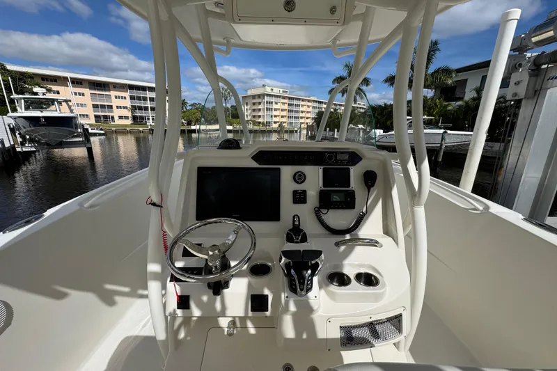 Slide: The Image of 2016 Sailfish 320 CC boat cockpit with steering wheel and control panel, docked near waterfront buildings. - 7