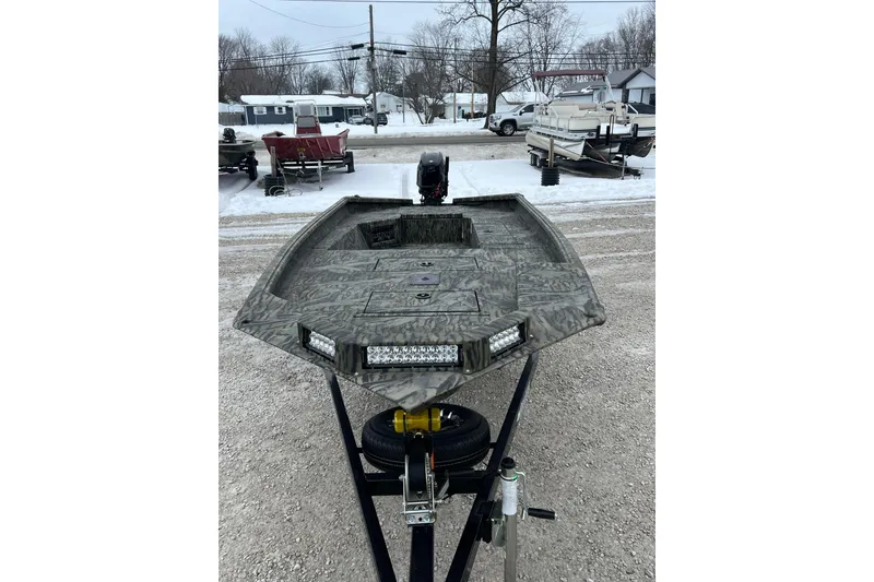 Slide: The Image of 2026 SeaArk 1752 Slayer X Pro boat on snowy lot, featuring camouflage design and LED lights. - 2