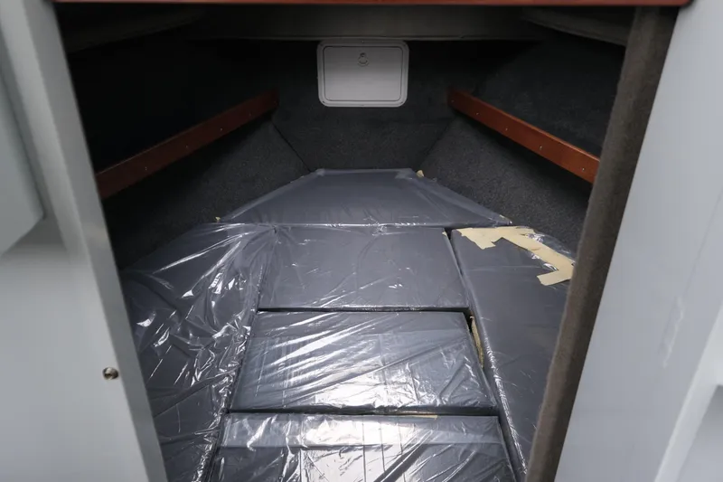 Slide: The Image of 2026 Hewescraft 270 Pacific Explorer cabin interior with plastic-covered bedding. - 13