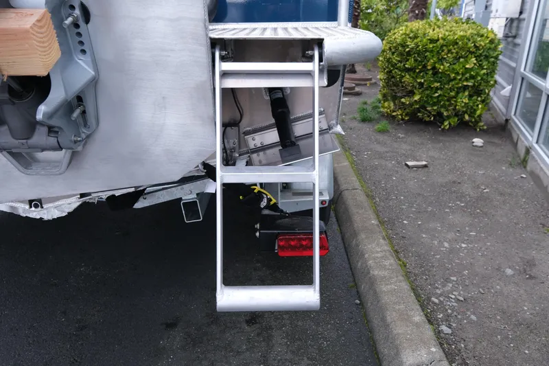 Slide: The Image of Rear view of 2026 Hewescraft 270 Pacific Explorer with ladder and trailer details. - 19