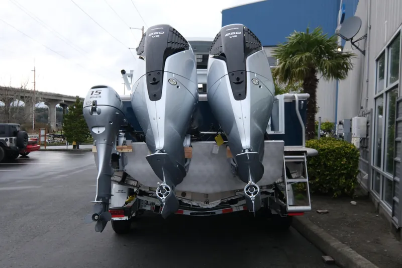 Slide: The Image of 2026 Hewescraft 270 Pacific Explorer with dual outboard motors in a parking lot. - 4
