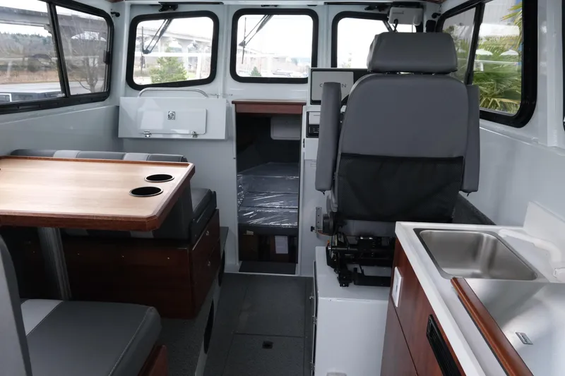 Slide: The Image of Interior of 2026 Hewescraft 270 Pacific Explorer, featuring seating, table, and kitchenette. - 7