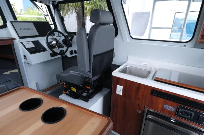 Slide: The Image of Interior of 2026 Hewescraft 270 Pacific Explorer with helm, sink, and seating. - 9