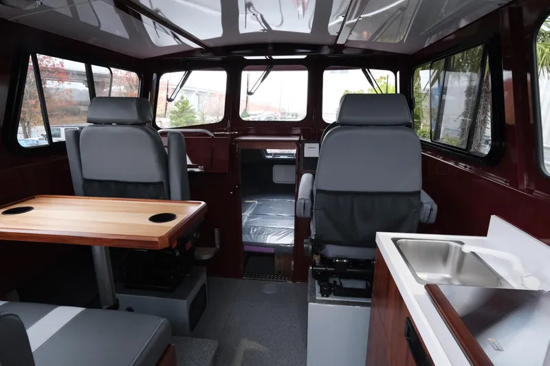 Slide: The Image of Interior of 2026 Hewescraft 240 Pacific Cruiser, featuring seating, table, and sink. - 10