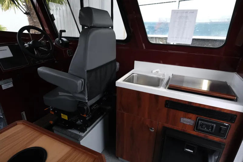Slide: The Image of Interior of 2026 Hewescraft 240 Pacific Cruiser with helm, seat, sink, and kitchenette. - 12