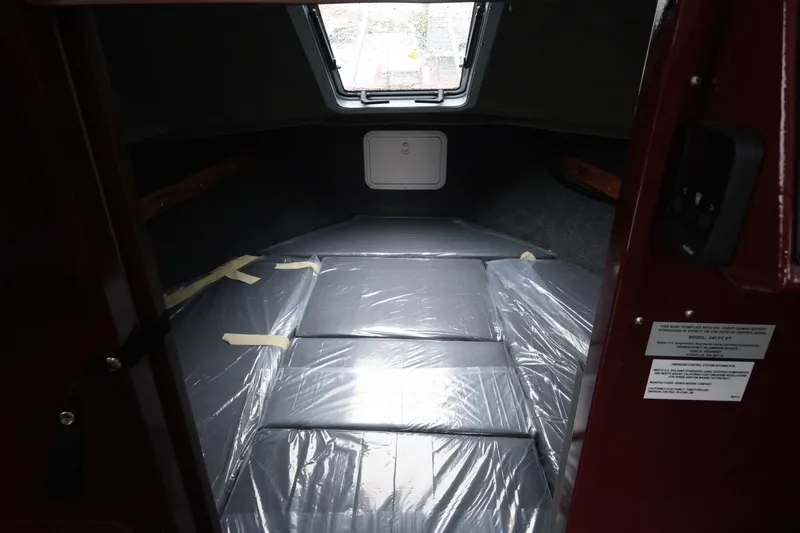 Slide: The Image of Interior cabin of 2026 Hewescraft 240 Pacific Cruiser, featuring a plastic-covered sleeping area. - 15
