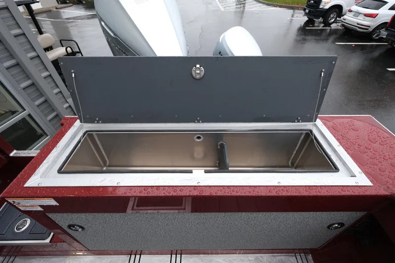 Slide: The Image of 2026 Hewescraft 240 Pacific Cruiser with open stainless steel compartment on a rainy day. - 23