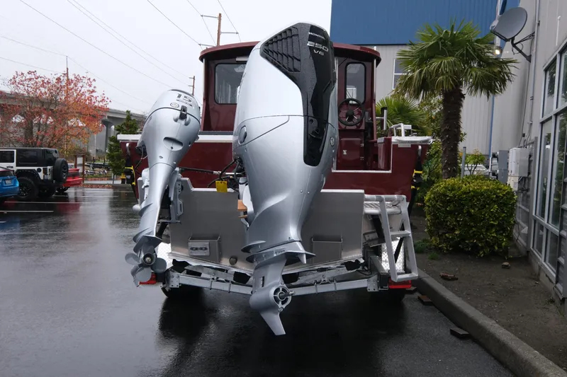 Slide: The Image of 2026 Hewescraft 240 Pacific Cruiser with dual outboard motors in a parking lot. - 5