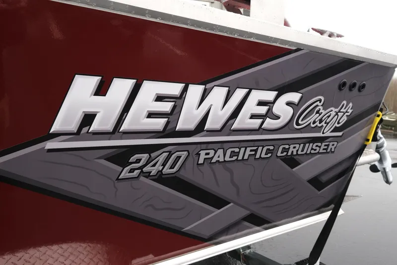 Slide: The Image of 2026 Hewescraft 240 Pacific Cruiser boat logo on red and gray hull. - 6