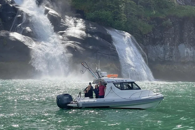 Slide: The Image of 2024 Flexboat 680 Explorer near a scenic waterfall, with passengers enjoying the view. - 18