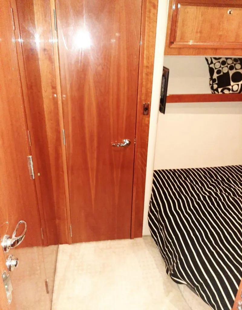 Slide: The Image of Interior of 2009 Riviera 47 Enclosed Flybridge Series II with wood finish and striped bedding. - 26