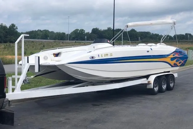 Slide: The Image of 2005 Conquest Top Cat boat on trailer with vibrant flame design, parked outdoors. - 3