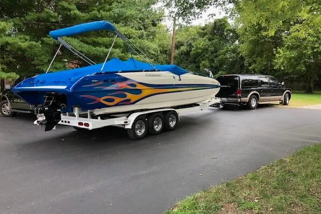 Slide: The Image of 2005 Conquest Top Cat boat with vibrant flame design on trailer, parked in driveway. - 4