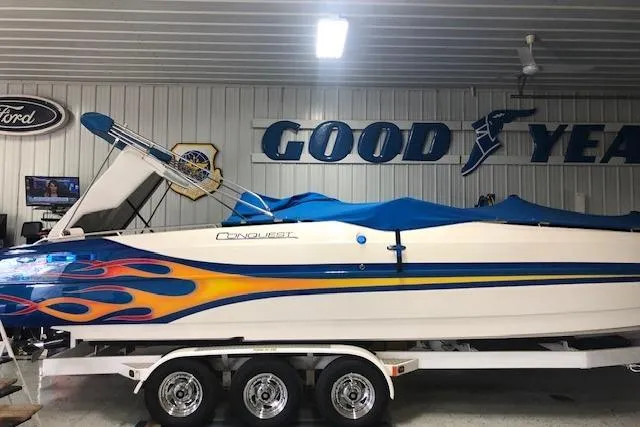 Slide: The Image of 2005 Conquest Top Cat boat with vibrant flame design in a garage setting. - 6