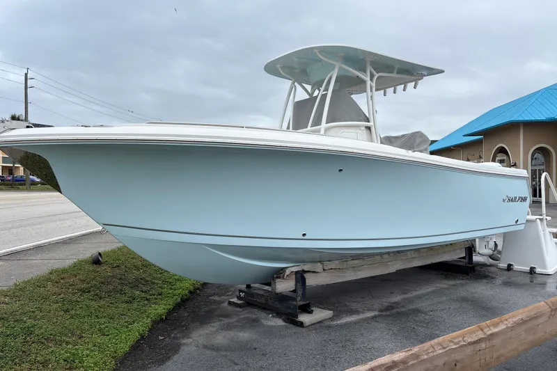 The Image of 2024 Sailfish 242 CC boat on display, light blue hull, parked outdoors. - 0
