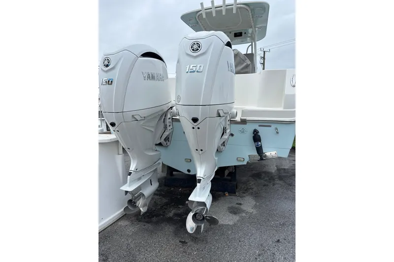 Slide: The Image of Twin Yamaha 150 engines on a 2024 Sailfish 242 CC boat, parked on wet pavement. - 2