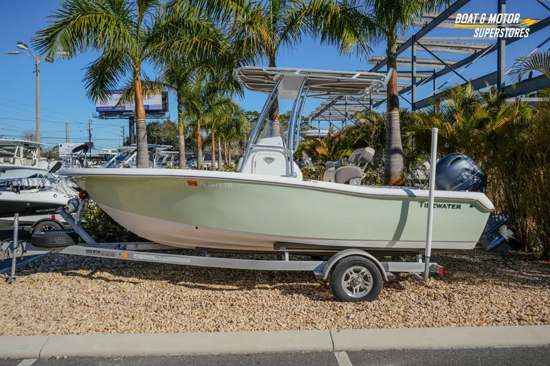 The Image of 2019 Tidewater 198 CC Adventure boat on trailer, surrounded by palm trees. - 1