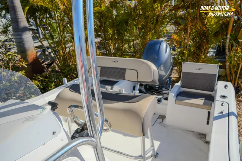 Slide: The Image of 2019 Tidewater 198 CC Adventure boat interior with seating and motor, surrounded by lush greenery. - 36