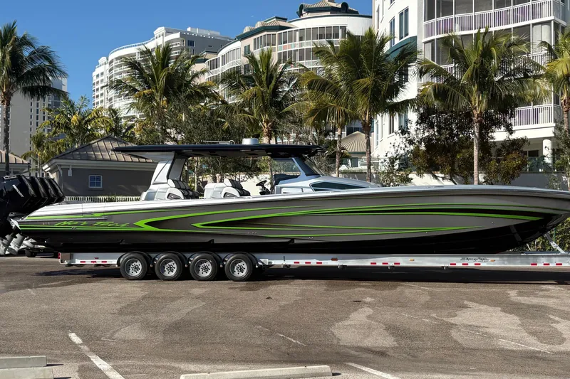 The Image of 2024 Nor-Tech boat with sleek design and green accents on a trailer, surrounded by palm trees. - 0