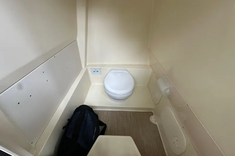 Slide: The Image of 2024 Chris-Craft Catalina 24 boat interior with compact toilet and storage space. - 24