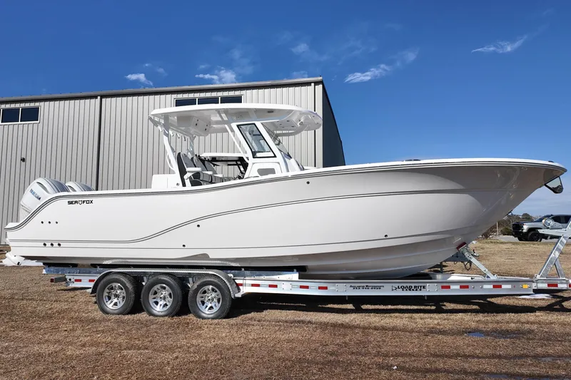 The Image of 2026 Sea Fox 328 Commander boat on trailer, parked outdoors under clear blue sky. - 0