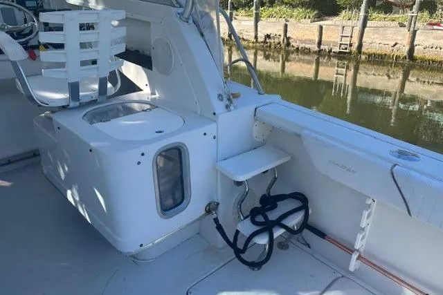 Slide: The Image of 2008 Glacier Bay 2670 Cuddy boat interior with seating and storage, docked by a calm waterway. - 17