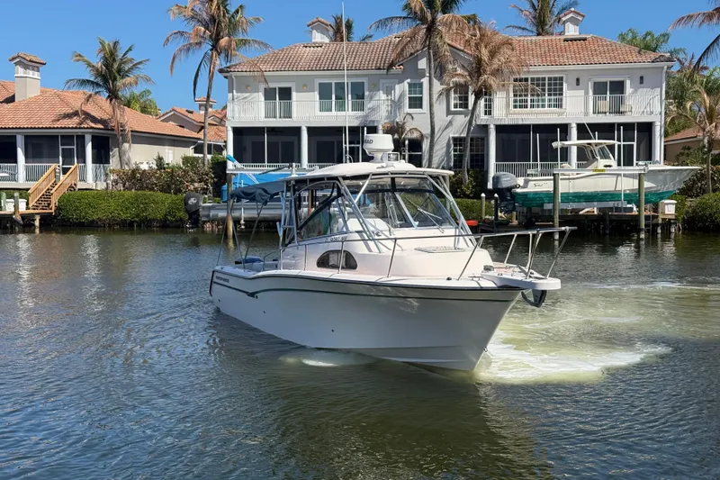 Slide: The Image of 2009 Grady-White Marlin 300 boat cruising near waterfront homes with palm trees. - 2