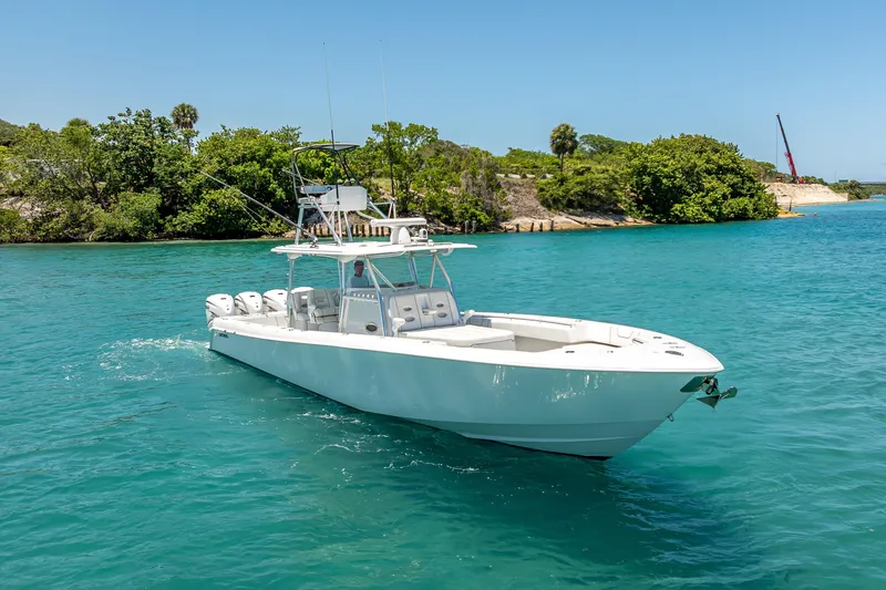 Slide: The Image of 2021 Contender 44 CB boat cruising in clear blue water near lush green shoreline. - 2