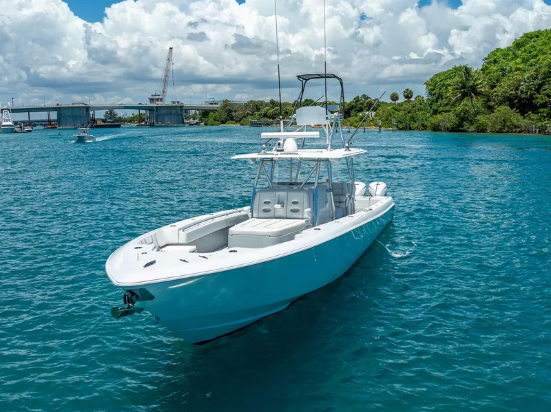Slide: The Image of 2021 Contender 44 CB boat on clear blue water near a bridge and lush greenery. - 8