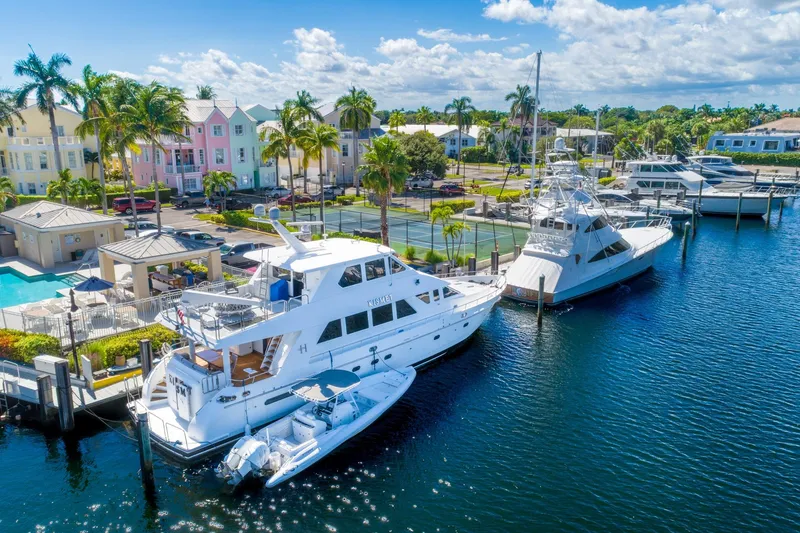 Slide: The Image of 2003 Hargrave Skylounge yacht docked at a vibrant marina with colorful buildings. - 2