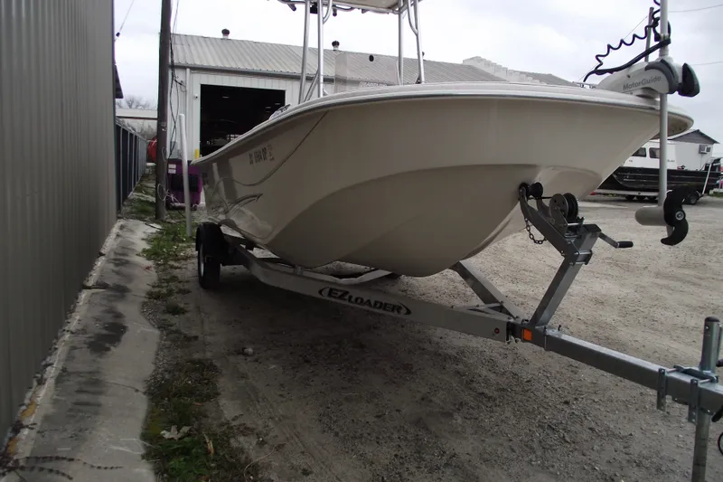 Slide: The Image of 2016 Carolina Skiff 198 DLV boat on trailer near a metal building. - 2