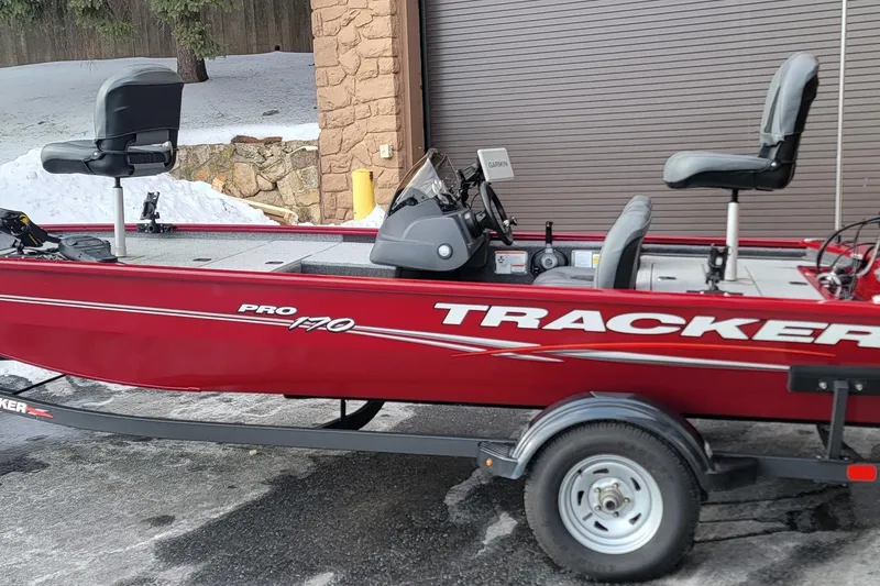 The Image of 2024 Tracker Pro 170 boat in red, parked on a trailer near a snowy area. - 1