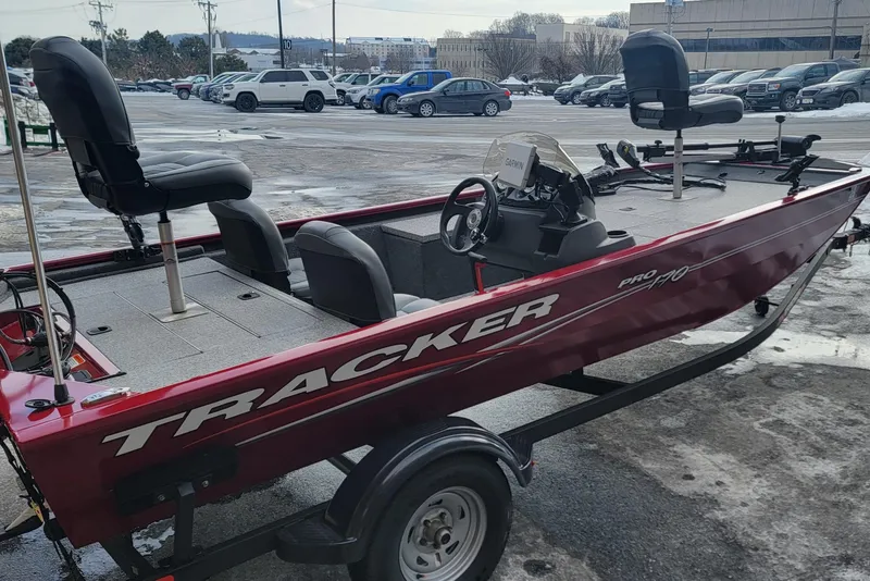 Slide: The Image of 2024 Tracker Pro 170 boat in parking lot, featuring red exterior and seating. - 6