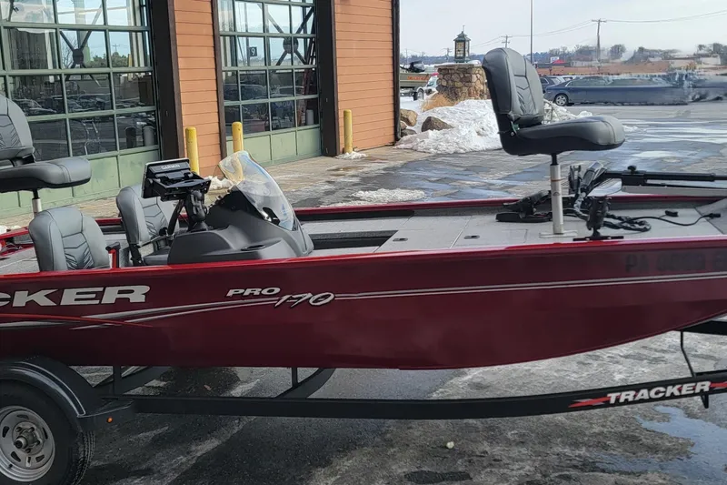 Slide: The Image of 2024 Tracker Pro 170 boat in red, parked outside a building with snow nearby. - 7