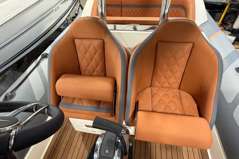 Slide: The Image of 2023 Cobra Ribs Nautique 8.2m boat interior with tan leather seats and wooden flooring. - 10