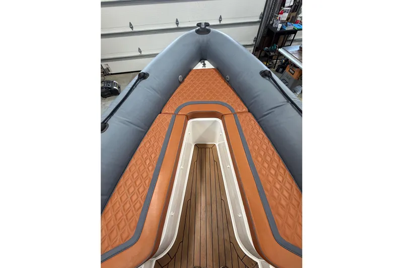 Slide: The Image of 2023 Cobra Ribs Nautique 8.2m boat interior with brown diamond-stitched seating and wooden flooring. - 5