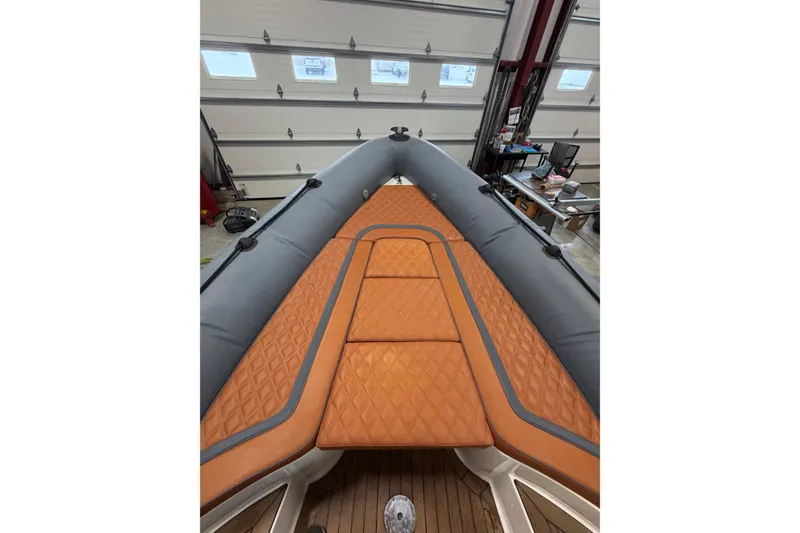 Slide: The Image of 2023 Cobra Ribs Nautique 8.2m boat with orange diamond-stitched seating in a garage. - 6