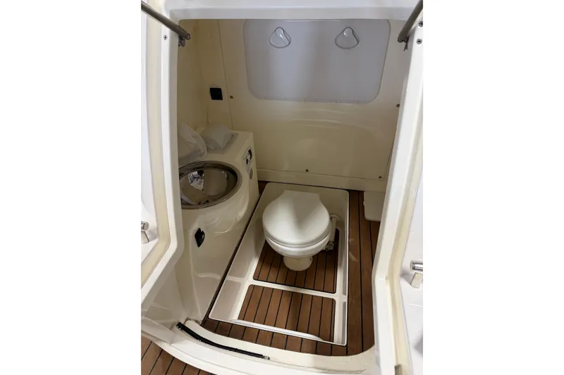 Slide: The Image of 2023 Cobra Ribs Nautique 8.2m boat interior with compact bathroom and wooden flooring. - 8
