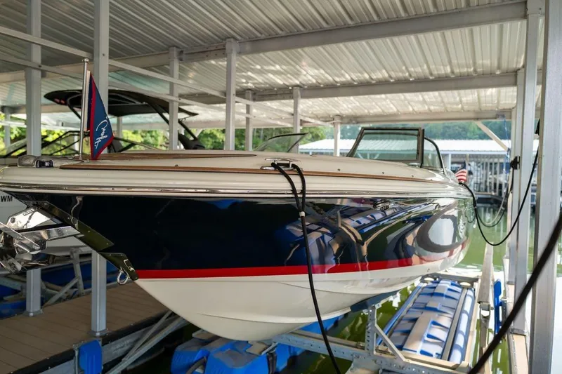 Slide: The Image of 2023 Chris-Craft Launch 27 boat docked under a covered marina. - 2