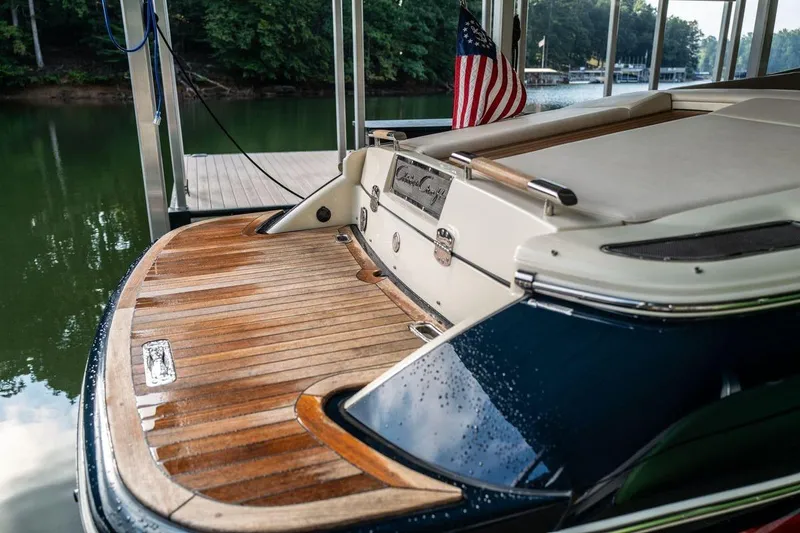 Slide: The Image of 2023 Chris-Craft Launch 27 boat with wooden deck, docked by a serene lake. - 9