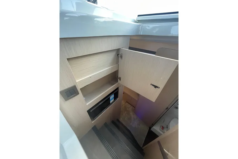 Slide: The Image of Interior view of 2026 Jeanneau TH38 yacht with open cabinet and stairs. - 62