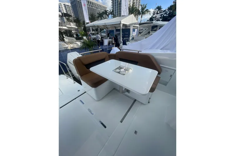 Slide: The Image of 2026 Jeanneau TH38 yacht interior with brown seating and white table at a boat show. - 90