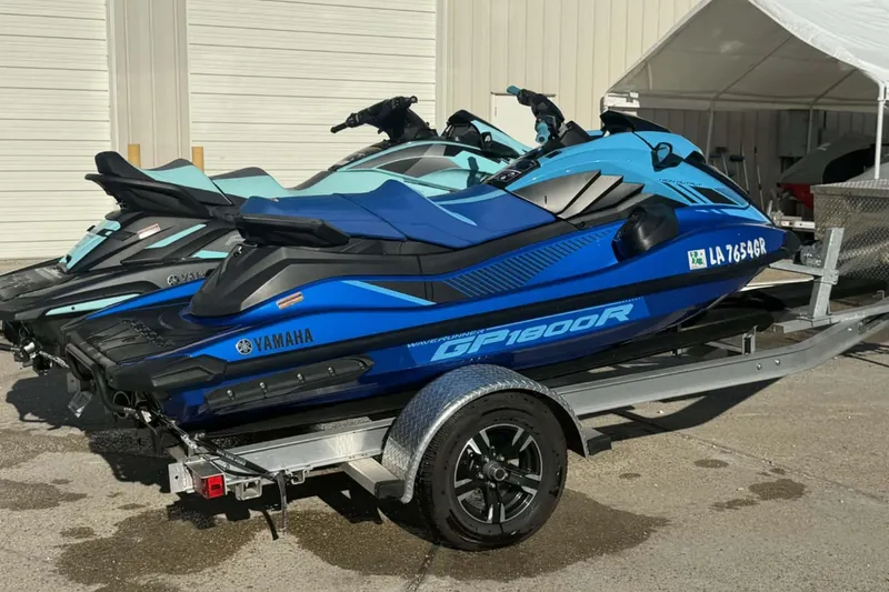 Slide: The Image of 2023 Yamaha WaveRunner GP1800R SVHO jet skis on a trailer, parked outdoors. - 5