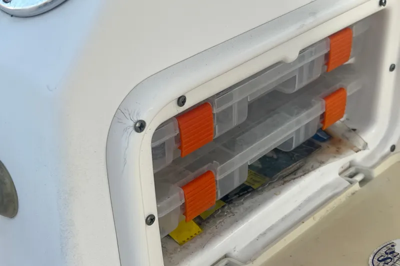 Slide: The Image of Storage compartment with orange-latched boxes on a 2011 Wellcraft 232 Coastal boat. - 16