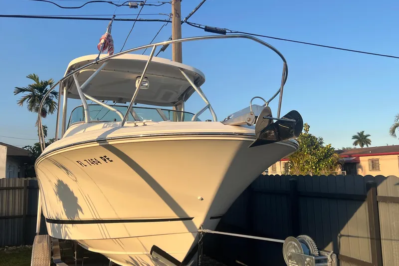 The Image of 2011 Wellcraft 232 Coastal boat on trailer, parked outdoors under clear blue sky. - 2